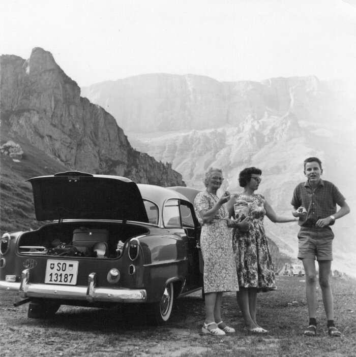 Foto Archiv Irmgard Bayard-Schärer: Drei Generationen meiner Familie beim stehenden Picknick: von links Grossmami Martha Kölliker, Mami Agnes Schärer-Kölliker und Bruder Beat Schärer neben dem ersten Auto der Familie.